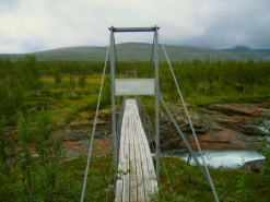 Gleich hinter der Koie berspannt eine Hngebrcke den Ruonekjahka. Noch hllt sich der Pass am Gabrel in Wolken.