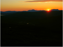 Bevor die Sonne hinter den Bergen untertaucht, bringt sie den Himmel zum Leuchten